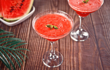 Watermelon refreshing summer frozen cocktail smoothie with watermelon slices and pieces on the background