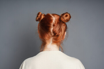 back view of red-haired woman with space buns hairstyle
