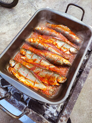 cooking rainbow trout on charcoal in a metal dish