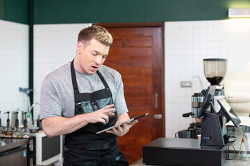 male barista using tablet and thinking something in coffee shop