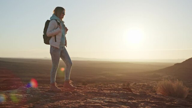 Travel concept slow motion with copy space, 4K American Will west landscape. Beautiful model with backpack walking in Monument Valley at sunrise with lens flare. Travel Arizona, USA text background