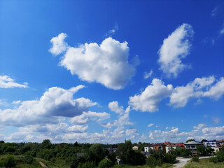 Piękne, letnie, błękitne niebo, pokryte chmurami nad osiedlem domów jednorodzinnych