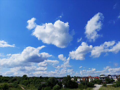 Piękne, letnie, błękitne niebo, pokryte chmurami nad osiedlem domów jednorodzinnych © clivio1
