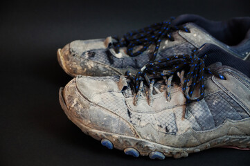 old dirty sneakers on a black background close up