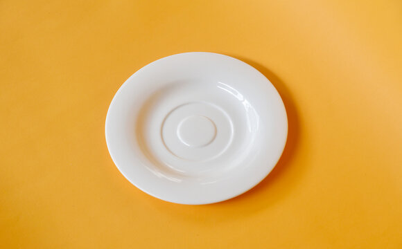 Empty Small White Plate Isolated On Yellow Background