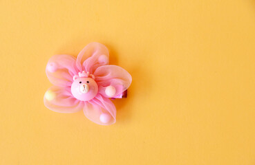 Obraz na płótnie Canvas Hair pin with flower motiv in pink color on yellow background