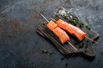 Raw salmon skewers for grilling in the Asian style on wooden board. Seafood barbecue Recipe, copy...