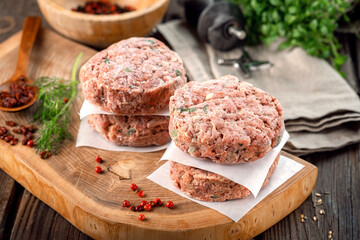 Frozen spicy pork patties with seasonings on table. Butcher minced meat cutlet