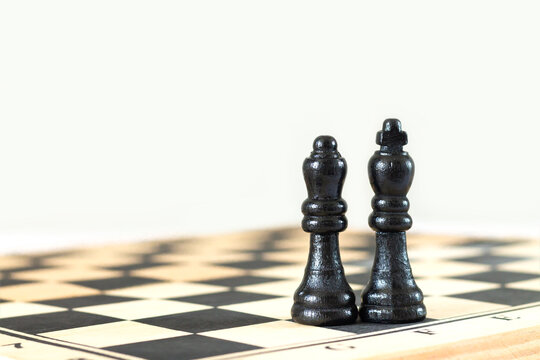 Black king and queen chess pieces on chessboard