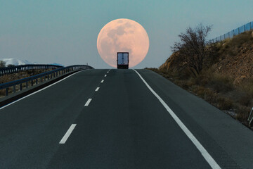 Refrigerated truck on a highway, at the top of a slope with the full moon in the background.