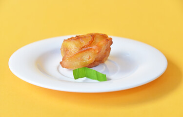 Crispy fried banana served on small white plate on color background