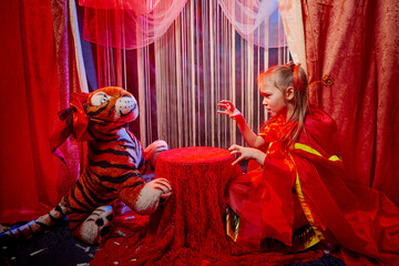 Small girl during a stylized theatrical circus photo shoot in a beautiful red location. Young model...