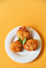 Crispy fried banana served on small white plate on color background