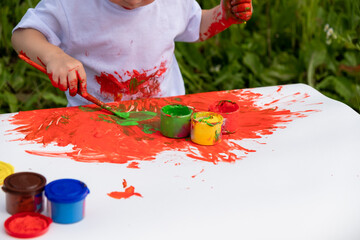 A cute little girl paints with a brush with krak on a white sheet of paper. Close-up.