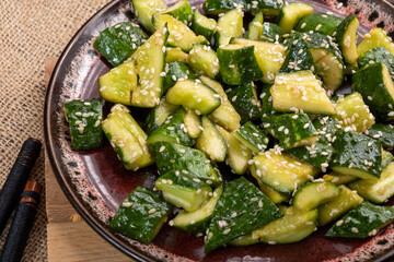 Broken cucumbers in a plate sprinkled with sesame seeds, close-up.