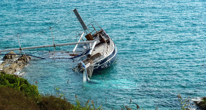 L Escalet, France - June 9. 2016: View on stranded sail ship with broken mast at rocky coastline of mediterranean sea (focus on boat)