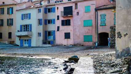 Fototapeta na wymiar St. Tropez, France - June 9. 2016: View on small pebble beach in village center with colorful houses in summer