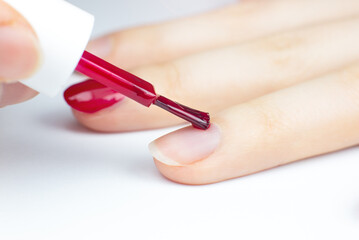 Woman applies red nail polish..Girl making a manicure. Salon procedures at home. Beautiful hands and nails. Close up, macro photo.