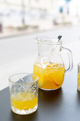 A pitcher of lemonade and a glass of lemonade in a summer cafe on the table