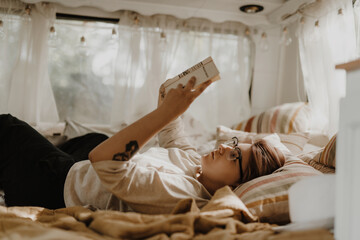 Beautiful woman reading book in a camper van.