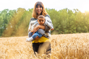 A young mother with her baby in a field of yellow straw in French Brittany in the summer of July, near the Broceliande forest. France
