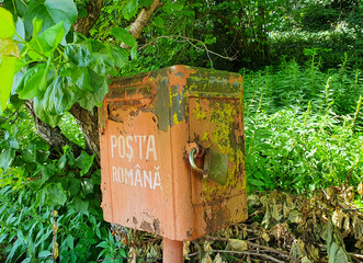 an old mailbox in vegetation with the Romanian Post inscription in the village of Ion Corvin - Romania