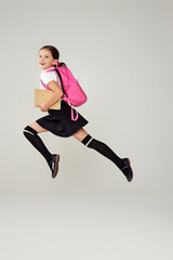 Fototapeta na wymiar cute happy schoolgirl jumping up with backpack