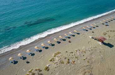 Aerial view of beach umbrellas in a row and lifeguard station on an empty beach. Paphos Cyprus