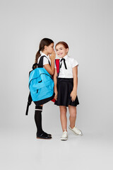 two happy little cheerful friends schoolgirls with backpacks