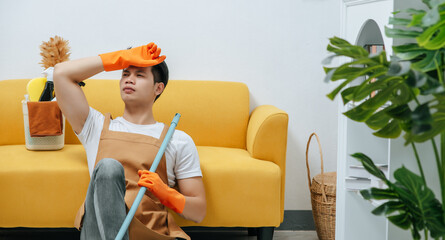 Young housekeeper man feel tired rest in living room