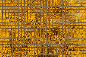 Texture of a wall made of small stones. The wall is clad with yellow granite cubes.