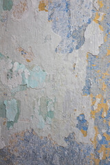 Peeling paint on the wall. Concrete wall with old yellow and blue cracked peeling paint