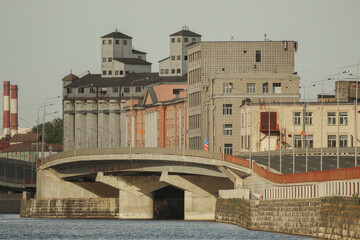 Urban landscape: modern bridge and old factory on the river bank