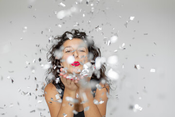 The emotion of success. Happy sexy brunette girl is enjoying celebrating with confetti on a white...