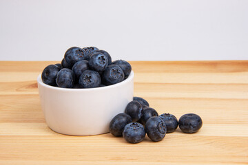 Fresh blueberry in white dish on wooden background copyspace