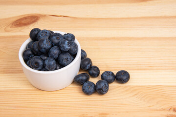 Fresh blueberry in white dish on wooden background copyspace