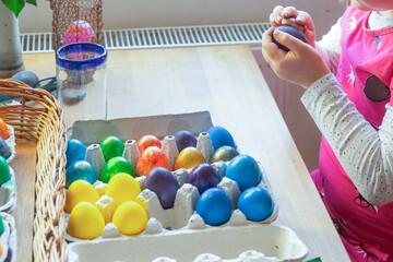 Children hands dyeing colorful Easter eggs.