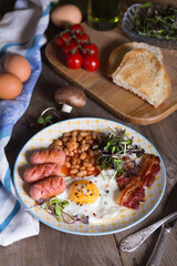 Fried eggs with bacon, sausages and beans in tomato sauce, English Breakfast