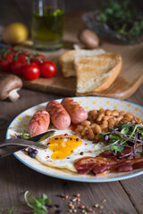 Fried eggs with bacon, sausages and beans in tomato sauce, English Breakfast