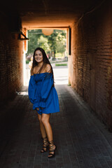 Fototapeta premium Portrait happy young woman wearing blue dress laughing looking at camera standing on street. Urban background