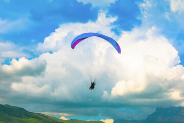 Blue paraglider on the background of beautiful clouds
