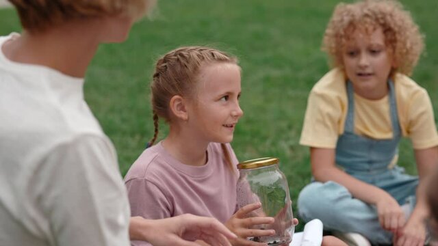 Female teacher giving botany lesson for children outdoors