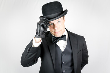 Portrait of British Gentleman in Dark Suit and Leather Gloves Politely Doffing Bowler Hat. Concept...