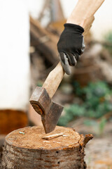 Man holding an ax. Ax in the stump. Chop wood. Firewood in the yard. Preparation of firewood for...