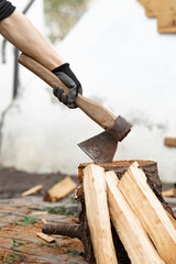 Man holding an ax. Ax in the stump. Chop wood. Firewood in the yard. Preparation of firewood for...
