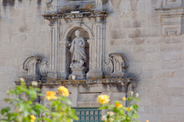 Fototapeta na wymiar Detalle fachada edificio religioso con flores desenfocadas en primer plano
