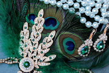 concept of roaring twenties, peacock feather, pearls and earrings with green stones