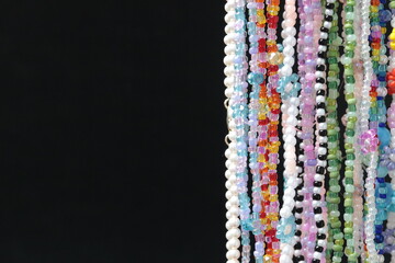 colorful pearl necklaces on a black background with copy space