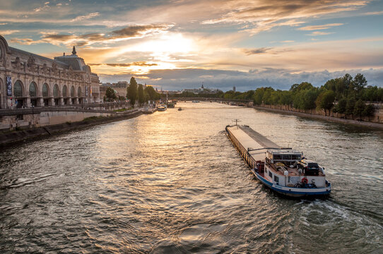 Transport fluvial sur la Seine vue du Pont Royal au crépuscule à Paris
