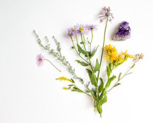 Purple and yellow wildflowers with leaves and amethyst flatlay isolated on white background